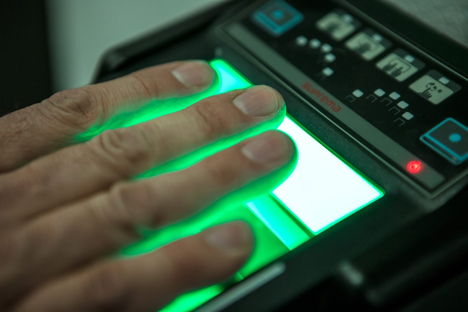 Mobile Live Scan Fingerprinting in Riverside & San Bernardino County A hand placing four fingers on the glowing green platen of a Live Scan fingerprint scanner